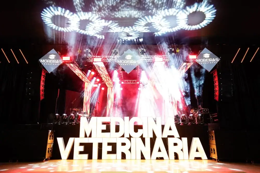 Palco iluminado da formatura com o letreiro do curso.